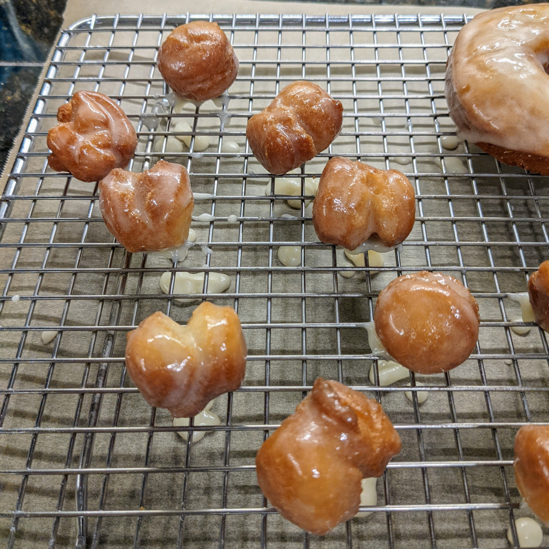 Several glazed, old-fashioned donut holes on a wire rack