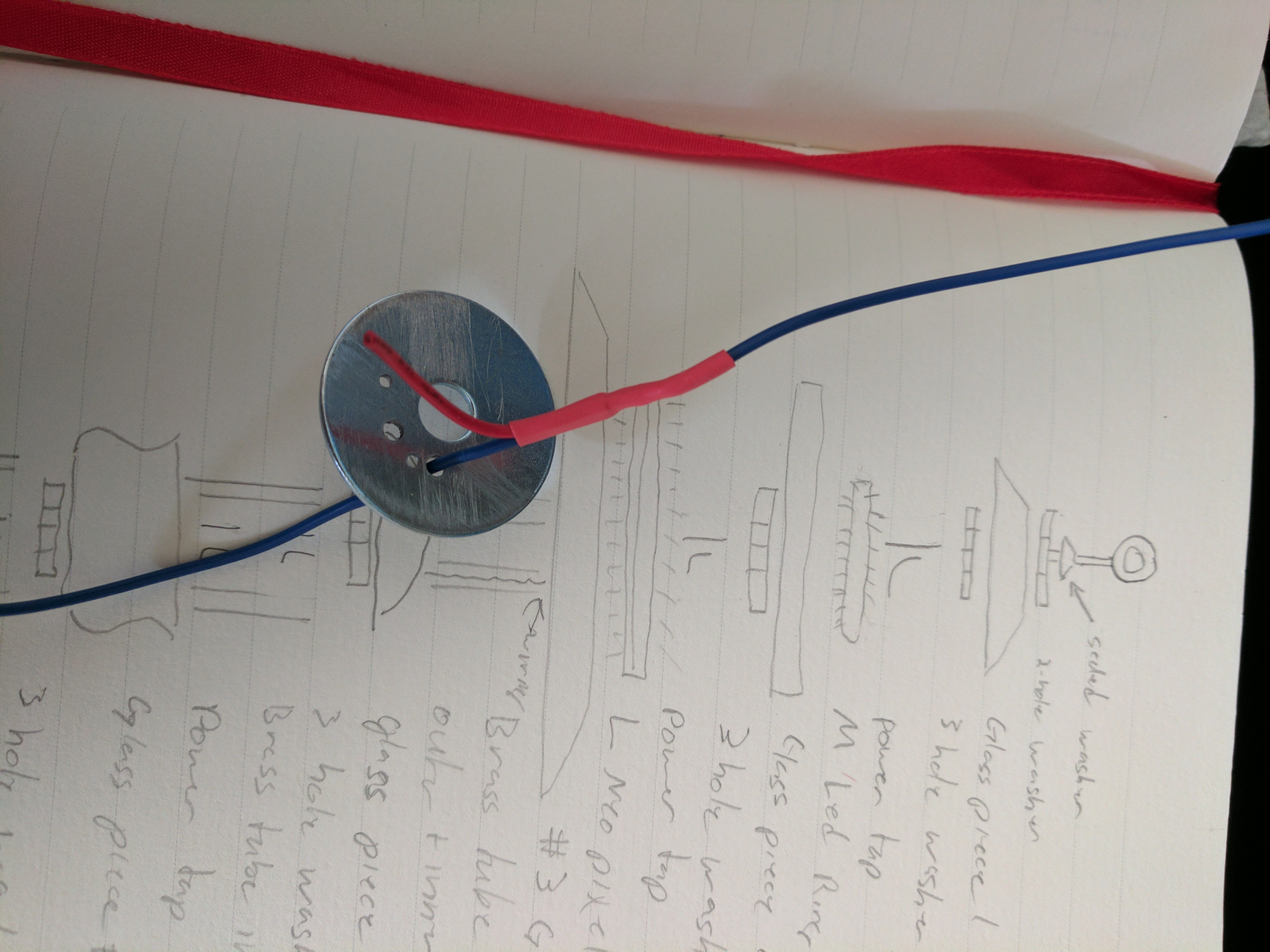 A notebook page with a diagram of the lantern.  A wire passing through a washer sits on top.