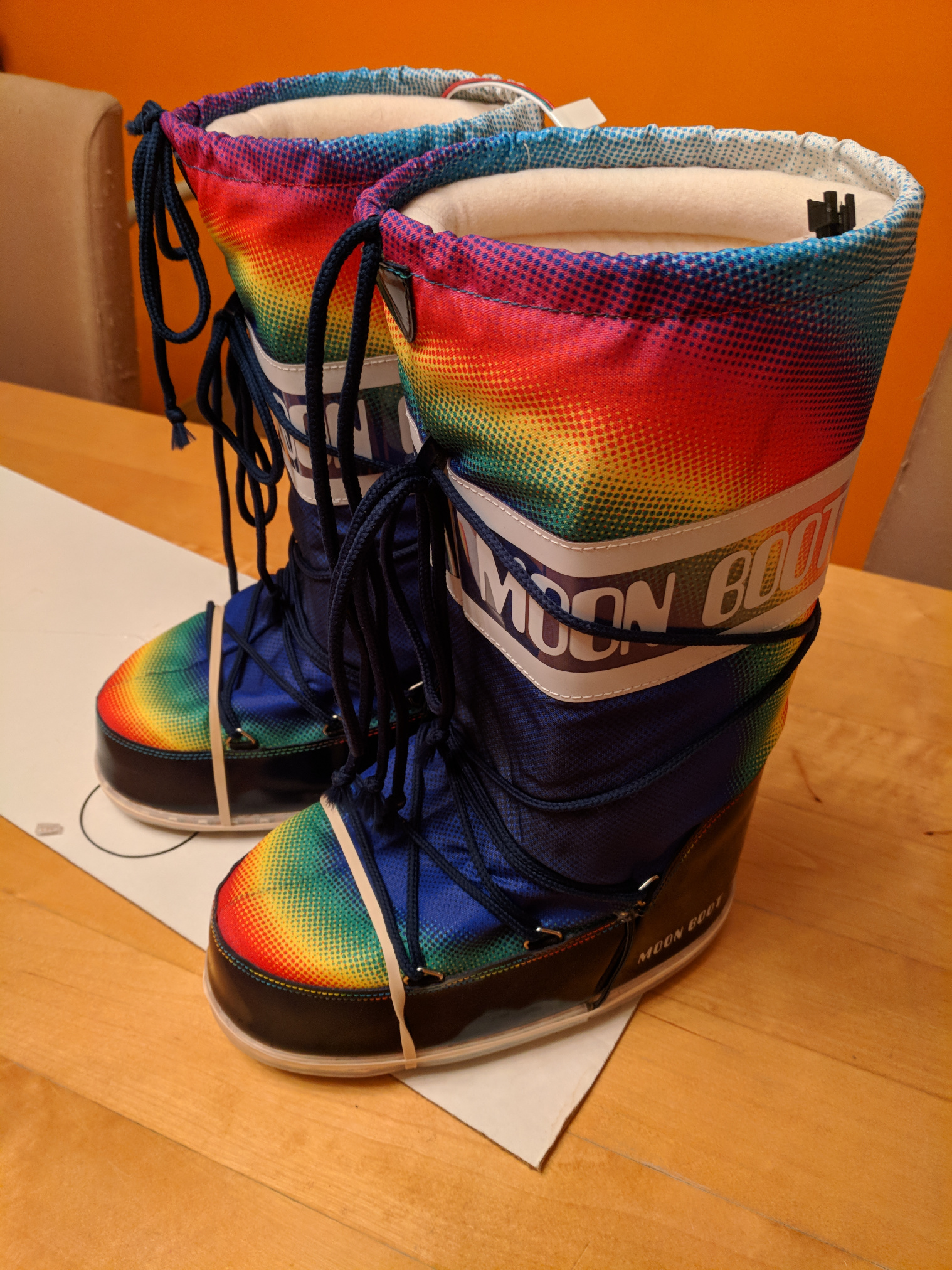A pair of rainbow moon boots with rubber bands around the toes to hold LED strips in place along the edge of the soles.