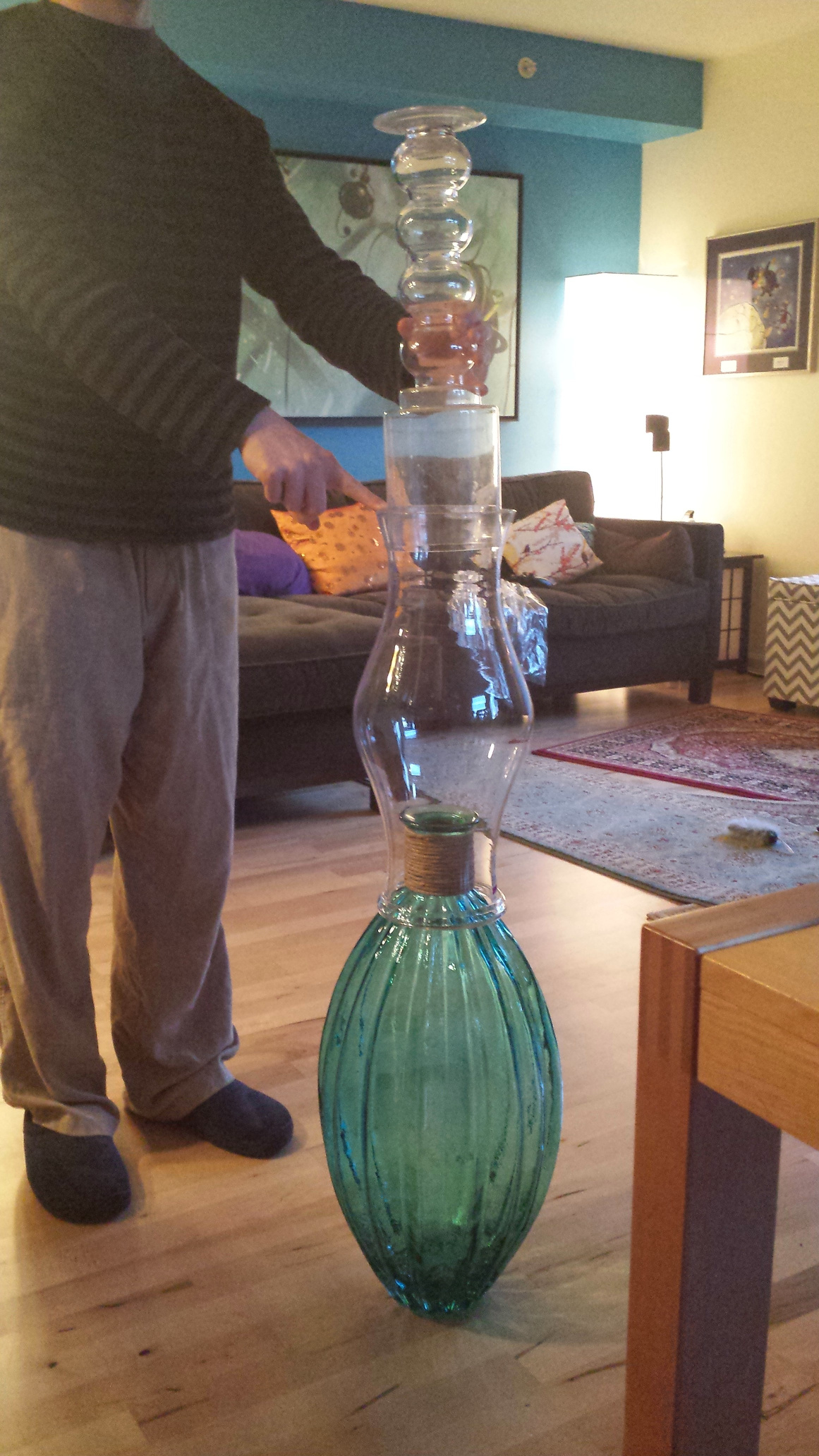Habib supporting a precarious looking stack of glass vases about shoulder height.