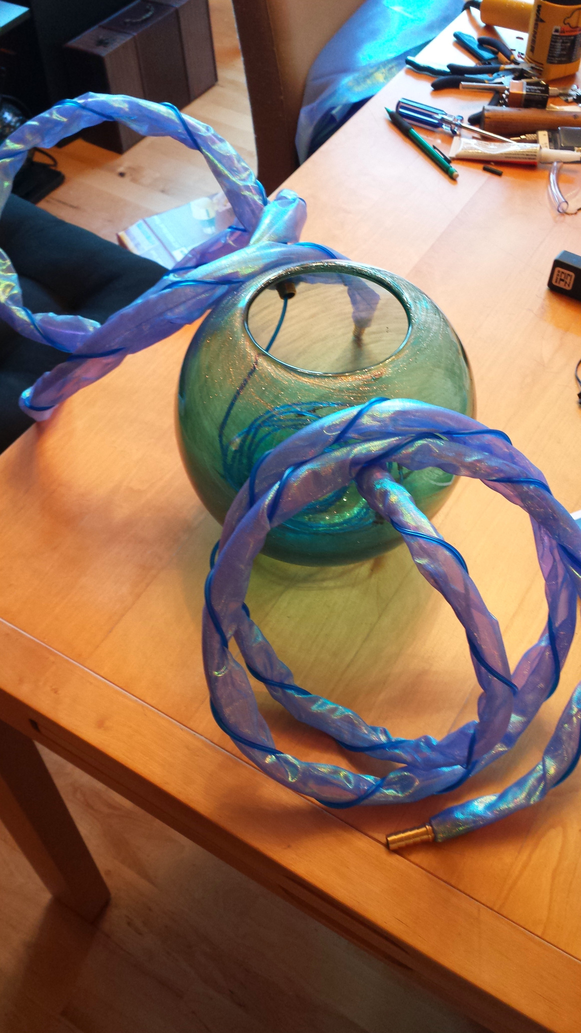 A globe style vase with two hoses coming out of the sides.  The hoses have been wrapped in fabric and a loose spiral of EL wire.