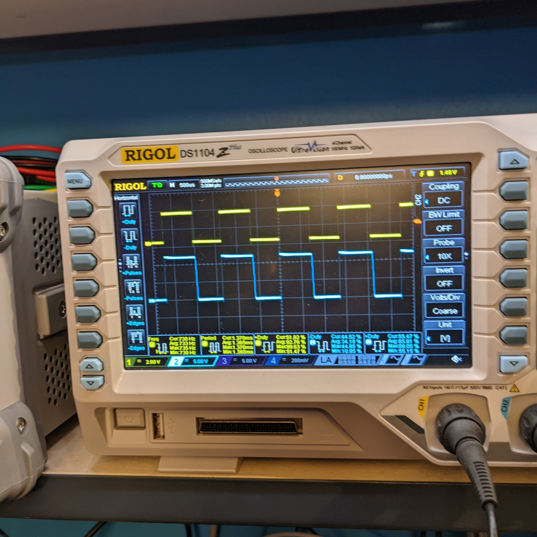 A close up of an oscilloscope displaying a pair of square waves
