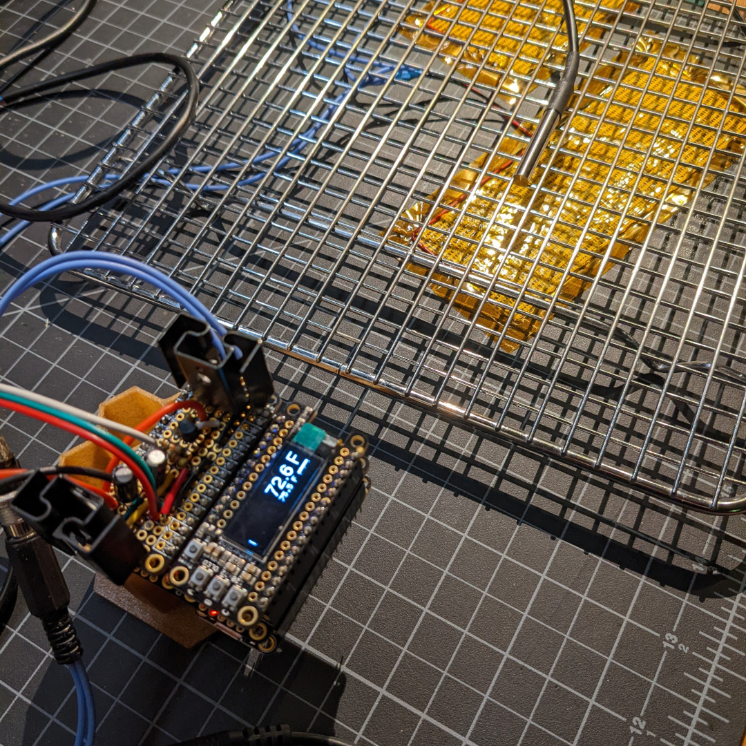 Circuit boards on a test bench connected to flat yellow heaters and a temperature sensor