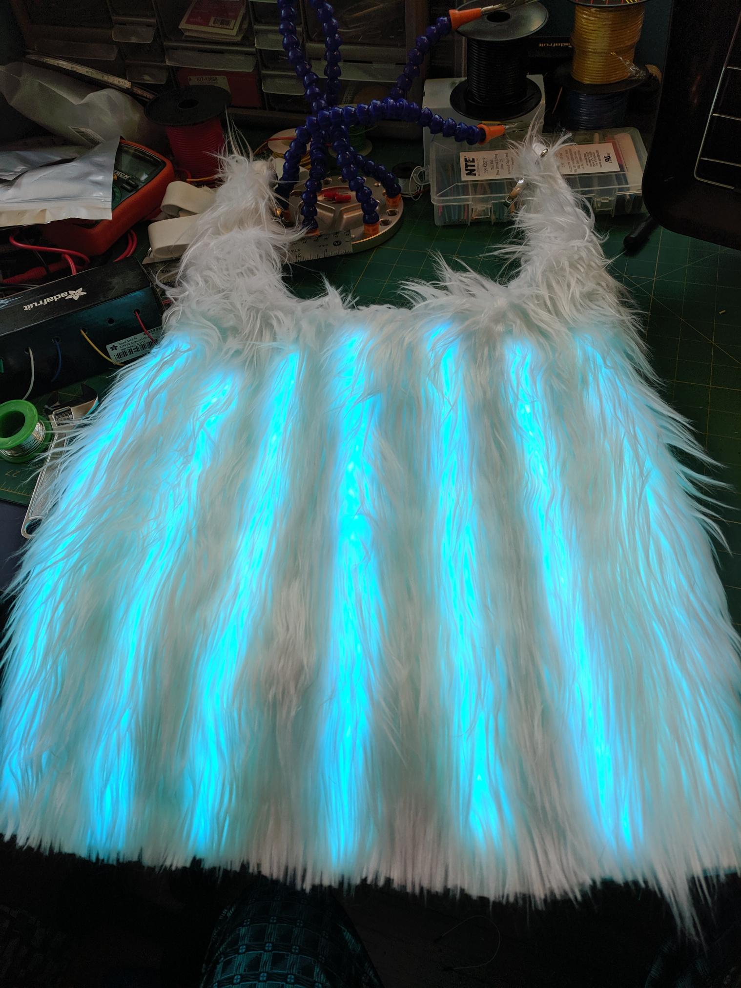 A white fur capelet with LED strips glowing through the fur.