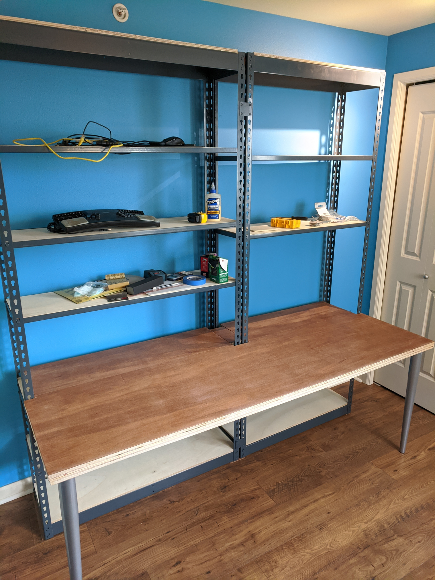 Desk built into the front of two metal rivet shelving units.